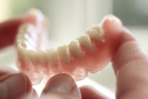 An image of dentures being held in someone's hand.