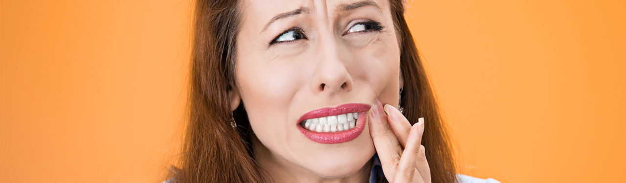 A woman suffering from a tooth ache that is a candidate for a root canal.