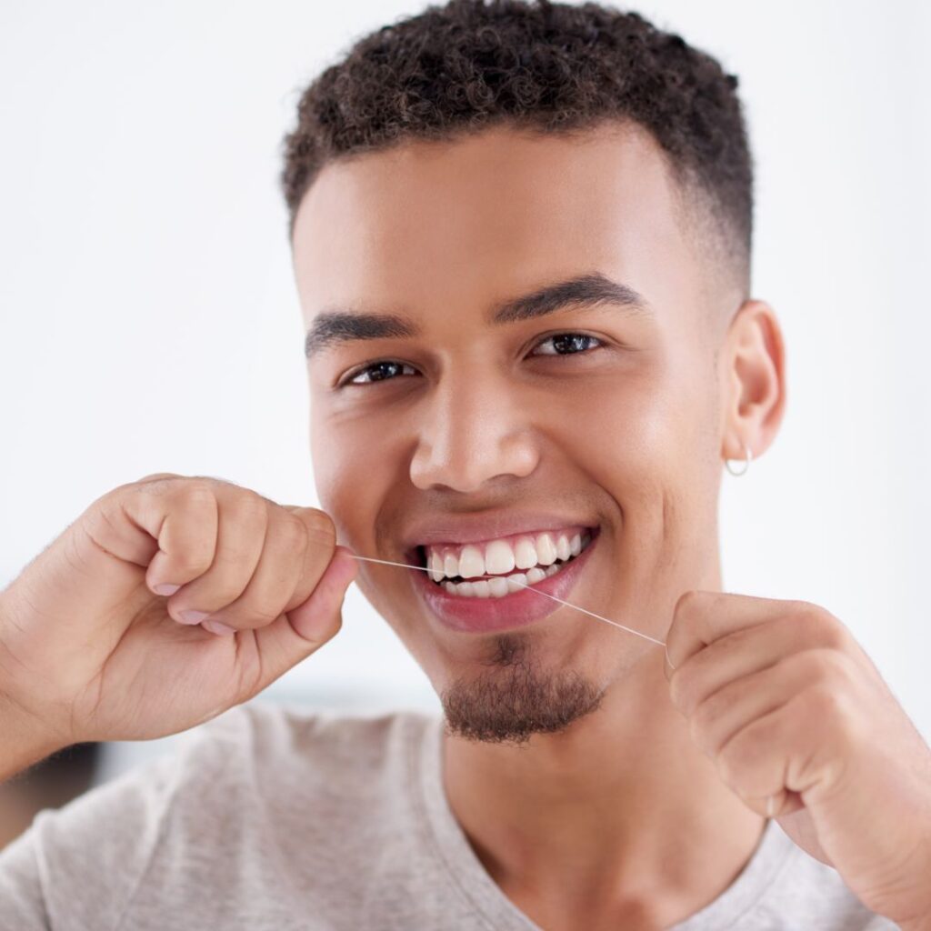 Guy Using Dental Floss In Bathroom