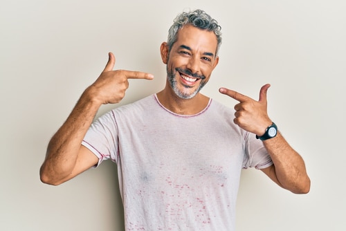 Middle age grey haired man wearing casual clothes smiling cheerful showing and pointing with fingers teeth and mouth