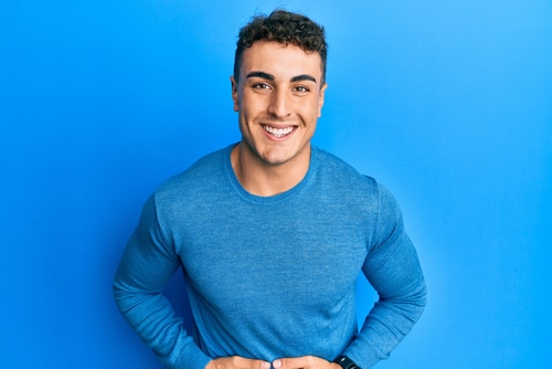 Hispanic young man wearing casual winter sweater smiling