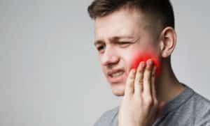 Frustrated young man touching his cheek and frowning face