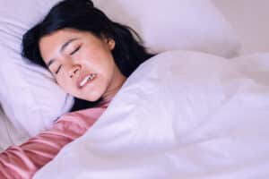 Asian,Woman,Sleeping,And,Grinding,Teeth,In,Bedroom,female,Tiredness,And