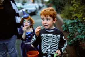 Little boy in skeleton costume eating halloween candy