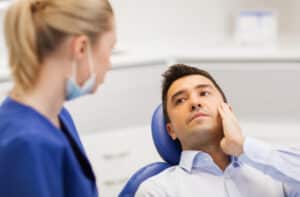Man talking to dental professional about pain in his tooth, which may be a sign of a tooth infection.