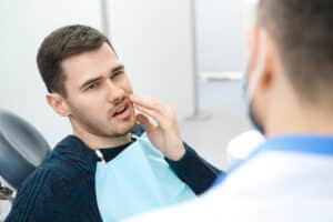 Man at the dentist getting dental treatment for intense tooth pain, possibly in need of root canal.